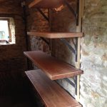 Old worktops with fabricated brackets for garden shelves